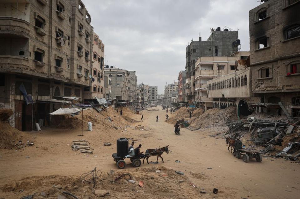 Palestinians walk between damaged buildings in Khan Yunis in the southern Gaza Strip on May 2, 2024, amid the ongoing conflict between Israel and the Hamas movement.