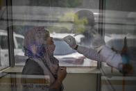 A health worker takes a swab sample to test for COVID-19 at a government hospital in Noida, a suburb of New Delhi, India, Wednesday, April 7, 2021. India hits another new peak with 115,736 coronavirus cases reported in the past 24 hours with New Delhi, Mumbai and dozens of other cities imposing night curfews to check the soaring infections. (AP Photo/Altaf Qadri)