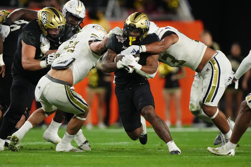 UCF running back RJ Harvey (7) runs the ball between Georgia Tech linebackers Kyle Efford (44) and Paul Moala (13) during the 2023 Gasparilla Bowl.