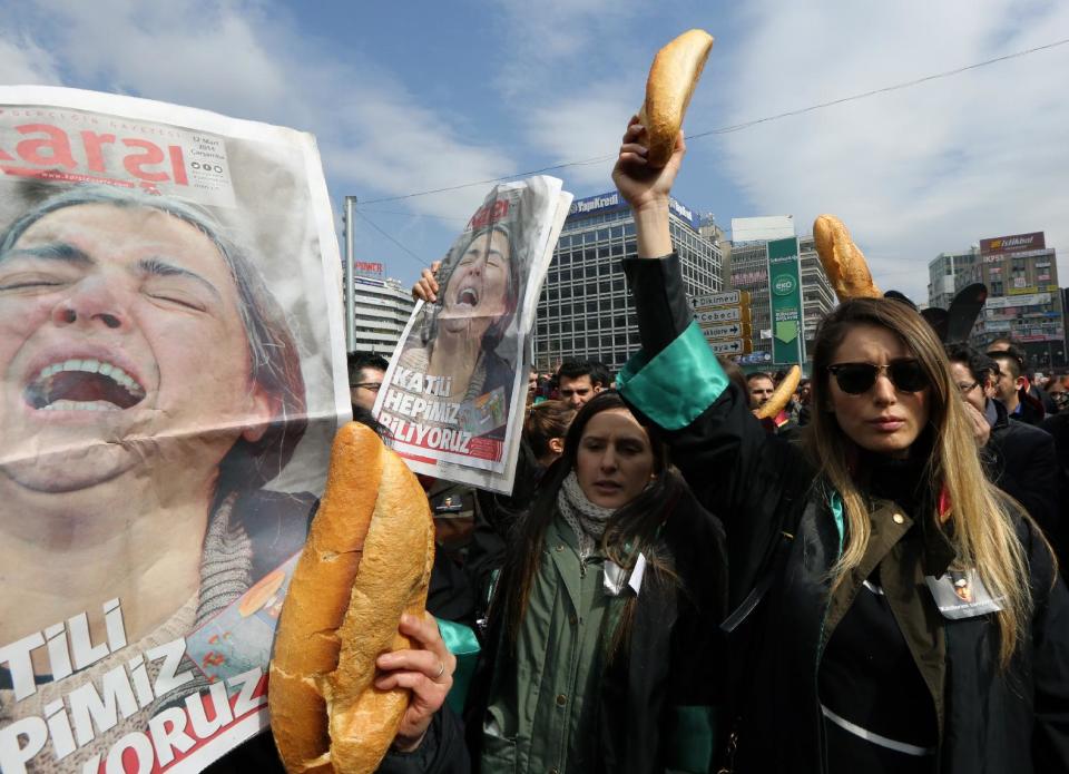 Turkish lawyers hold loaves of bread and newspapers with a photo of Gulsum Elvan, the mother of Berkin Elvan, a Turkish teenager who has died but who was in a coma since being hit on the head by a tear gas canister fired by police during last summer's anti-government protests, during a protest in Ankara, Turkey, Wednesday, March 12, 2014. On Wednesday, thousands converged in front of a house of worship in Istanbul calling for Prime Minister Recep Tayyip Erdogan to resign. Elvan, who turned 15 in January, was caught up in the protests on his way to a shop to buy bread.(AP Photo/Burhan Ozbilici)
