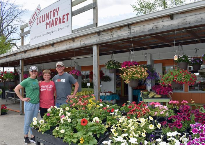 The new owners of Slim's Country Market, Jessica and Kent Allen, pose in front of their business along with their son, Arrow.