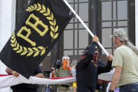 FILE - In this Sept. 7, 2020 photo, a protester carries a Proud Boys banner, symbol of a right-wing group, while other members start to unfurl a large U.S. flag in front of the Oregon State Capitol in Salem, Ore. President Donald Trump didn't condemn white supremacist groups and their role in violence in some American cities this summer. Instead, he said the violence is a “left-wing" problem and he told one far-right extremist group to “stand back and stand by.” His comments Tuesday night were in response to debate moderator Chris Wallace asking if he would condemn white supremacists and militia groups. Trump's exchange with Democrat Joe Biden left the extremist group Proud Boys celebrating what some of its members saw as tacit approval. (AP Photo/Andrew Selsky, File)