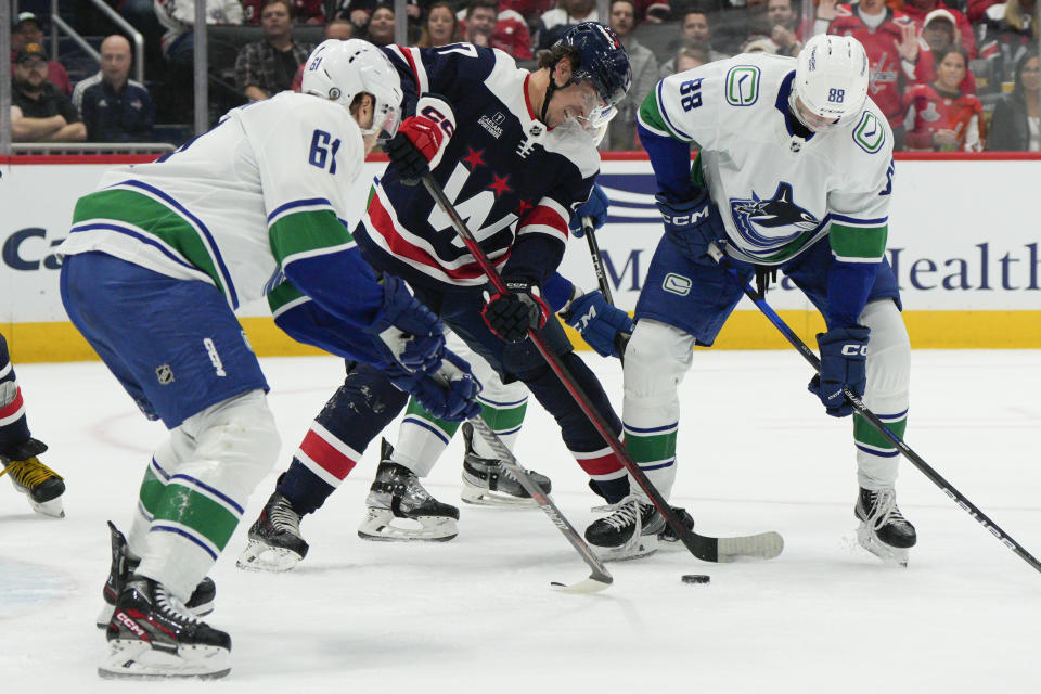 Vancouver Canucks defenseman Riley Stillman (61) and center Nils Aman (88) battle Washington Capitals center Dylan Strome (17) for the puck in front of the net during the first period of an NHL hockey game, Monday, Oct. 17, 2022, in Washington. (AP Photo/Jess Rapfogel)