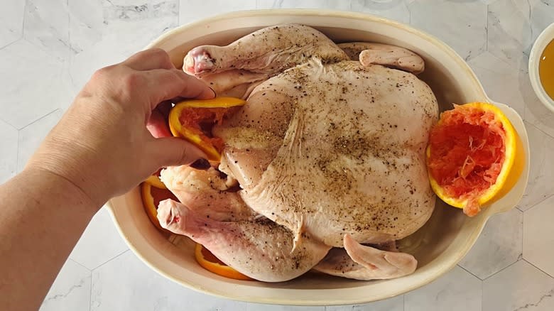 hand stuffing chicken with orange rinds