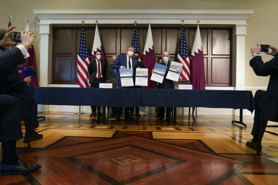 Stan Deal, President and CEO Boeing Commercial Airplanes, left, and Qatar Airways' CEO Akbar al-Baker, right, hold up signed agreements for the purchase of thirty-four 777-8 Freighter planes with purchase rights for an additional sixteen, in the Eisenhower Executive Office Building on the White House Campus in Washington, Monday, Jan. 31, 2022. Standing behind from left are Brian Deese, David Calhoun, CEO, The Boeing Company, Qatar's Emir Sheikh Tamim bin Hamad Al Thani and Secretary of Commerce Gina Raimondo. They also signed a letter of intent for an additional purchase from Qatar Airways of twenty-five 737-10s , worth $6.7 billion. (AP Photo/Carolyn Kaster)