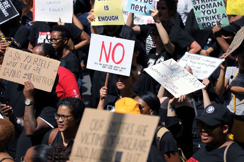 FILE PHOTO: Women hold placards as they protest against gender-based violence, outside the Johannesburg Stock Exchange in Sandton, Johannesburg