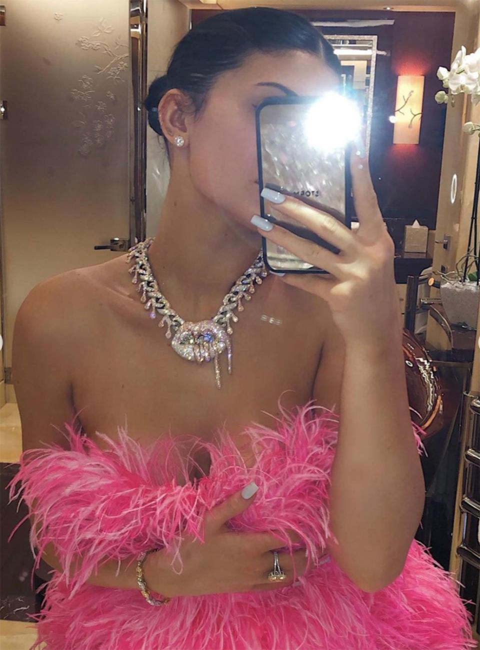 She accessorized her hot pink feather mini-dress with a diamond necklace gifted to her by Travis Scott. 