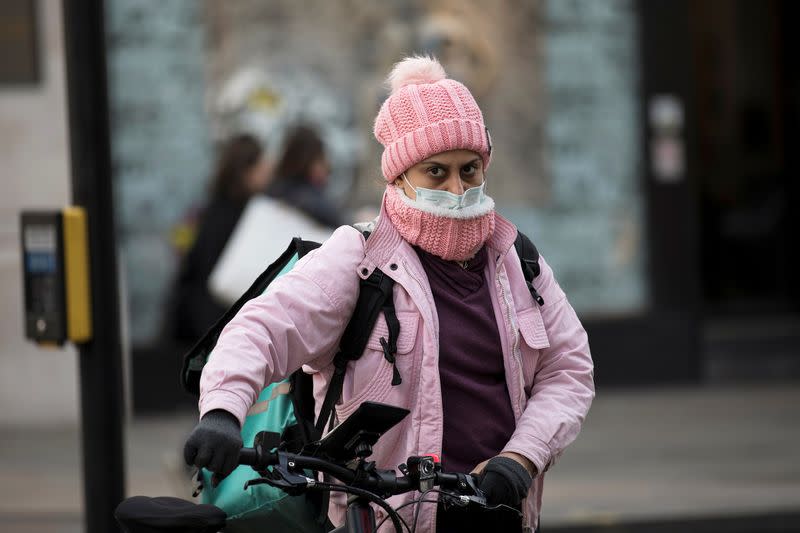 A woman wears a protective mask as she walks on Oxford Street in London