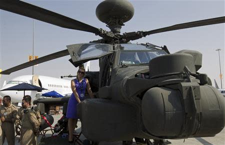 A visitor poses for a picture on a military helicopter during the Dubai Airshow November 18, 2013. REUTERS/Caren Firouz