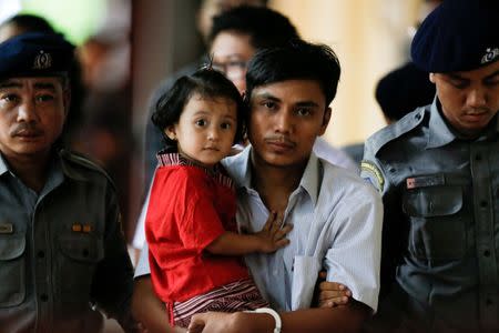Detained Reuters journalist Kyaw Soe Oo carries his daughter Moe Thin Wai Zin while escorted by police during a court hearing in Yangon, Myanmar, June 5, 2018. REUTERS/Ann Wang/Files