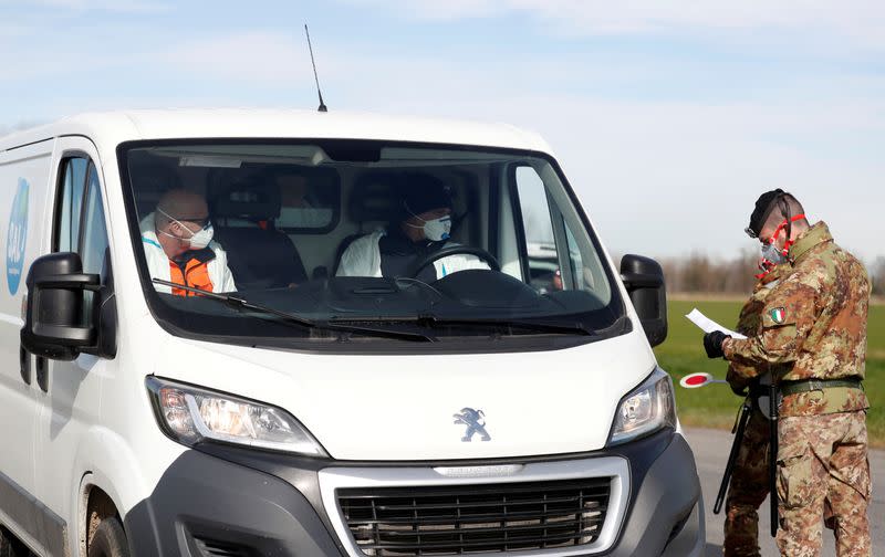 Members of the Italian army wearing protective face masks check the permission of a driver to enter the cordoned areas in a "check-point six" few kilometers from the small town of Castiglione d'Adda