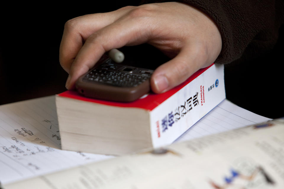 In this Sunday, Feb. 26, 2012 photo, a student rests his hand on a Chinese-French dictionary during a French course of Alliance Francaise, an organization that promotes French language and culture, in Tianjin, China. Thousands of people in China are trying to write their own ticket out of the country - in French. Chinese desperate to emigrate have discovered a backdoor into Canada that involves applying for entry into the country's francophone province of Quebec - as long as you have a good working knowledge of the local lingo. (AP Photo/Alexander F. Yuan)
