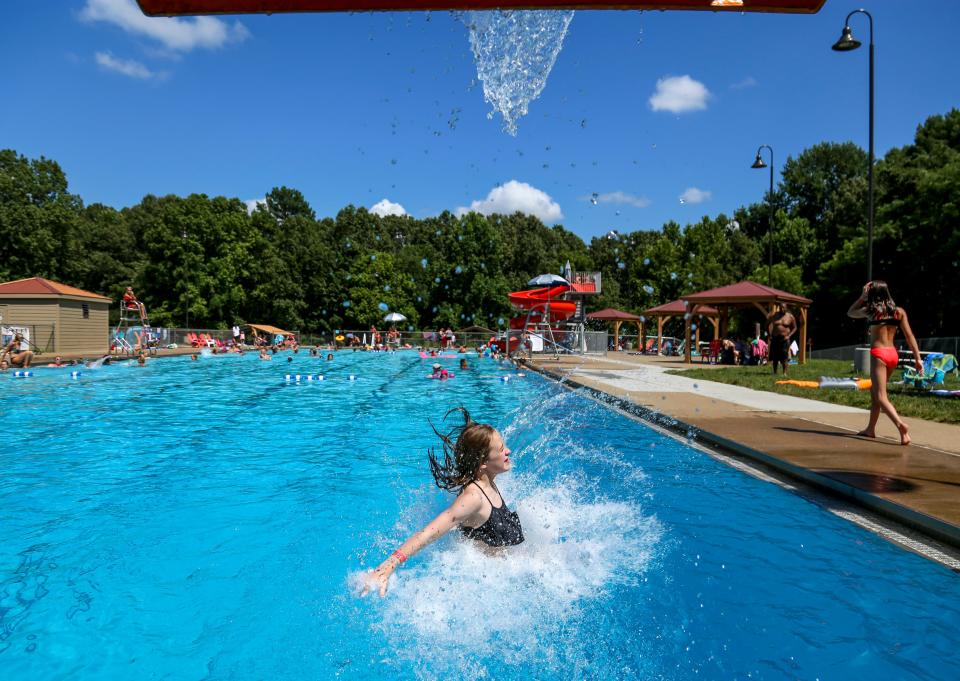 Pool-goers emerge from the mouth of a slide and splash into the water at Swan Lake Pool in Clarksville, Tenn., on Saturday, July 20, 2019. 