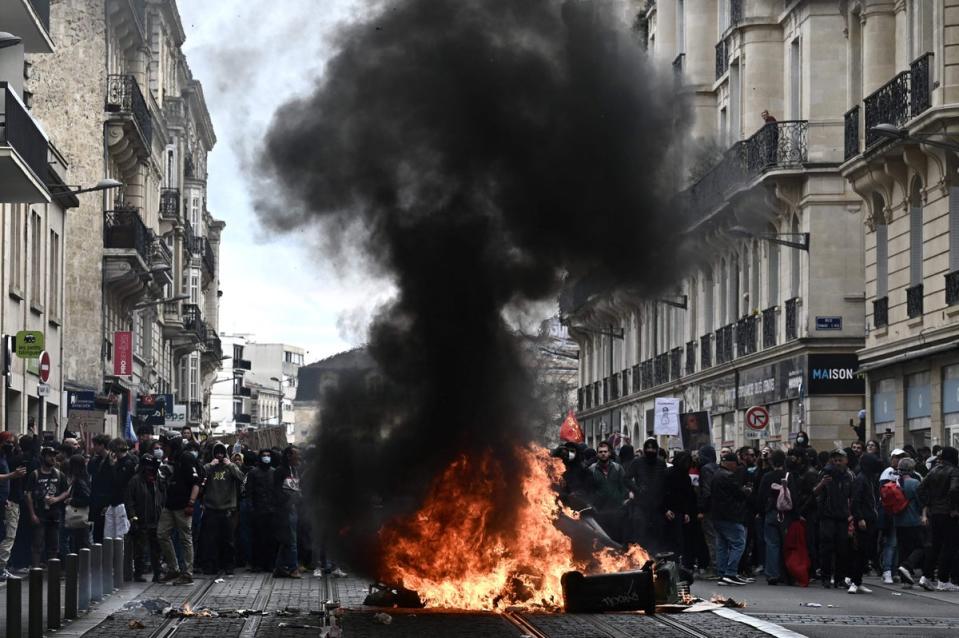 People stand behind a fire during a demonstration, a week after the government pushed a pensions reform through parliament without a vote, using the article 49.3 of the constitution, in Bordeaux, western France (AFP via Getty Images)