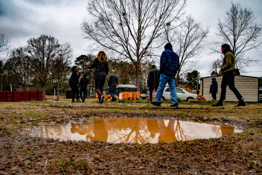 People walking past a large puddle of brown water