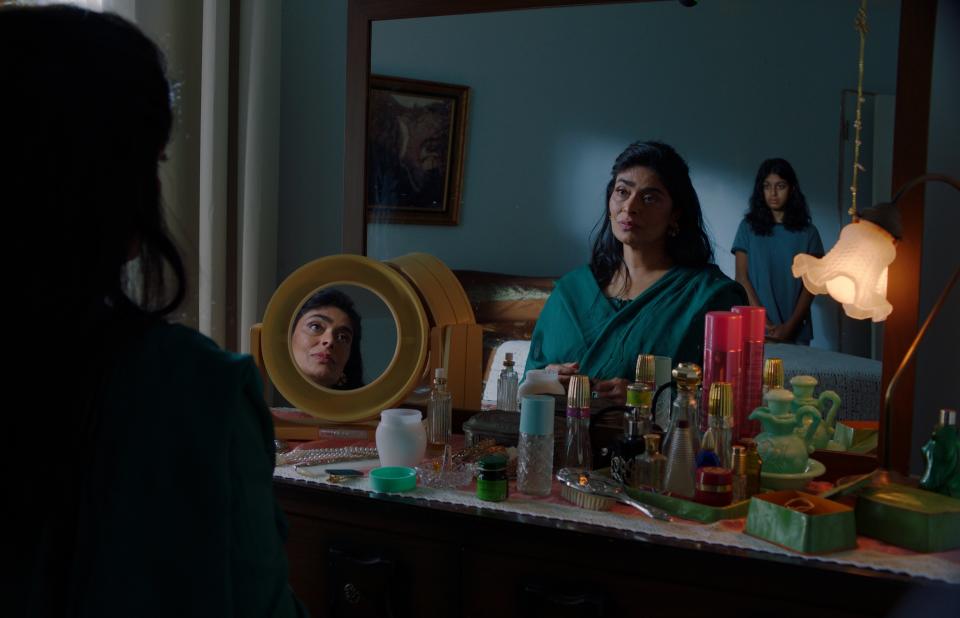 A young teen girl stands behind her mother, who sits at a vanity table; still from "The Queen of My Dreams"