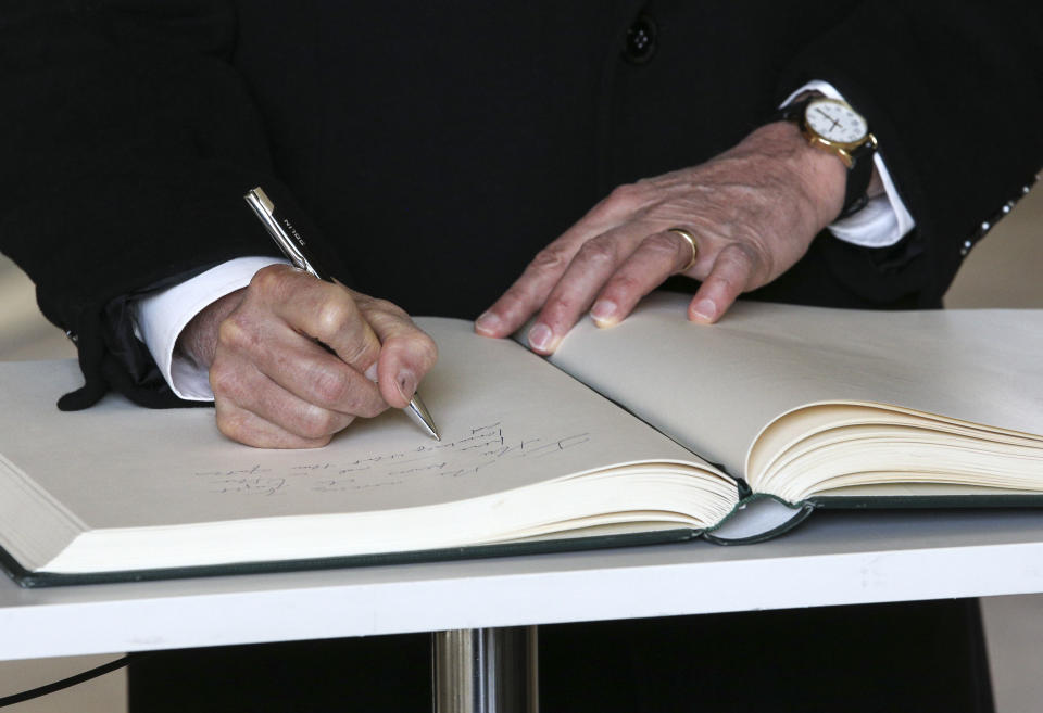 United States Vice President Mike Pence writes in the guest book at the Monument to the Ghetto Heroes after a wreath laying ceremony in Warsaw, Poland, Thursday, Feb. 14, 2019. The Polish capital is host for a two-day international conference on the Middle East, co-organized by Poland and the United States. (AP Photo/Michael Sohn)