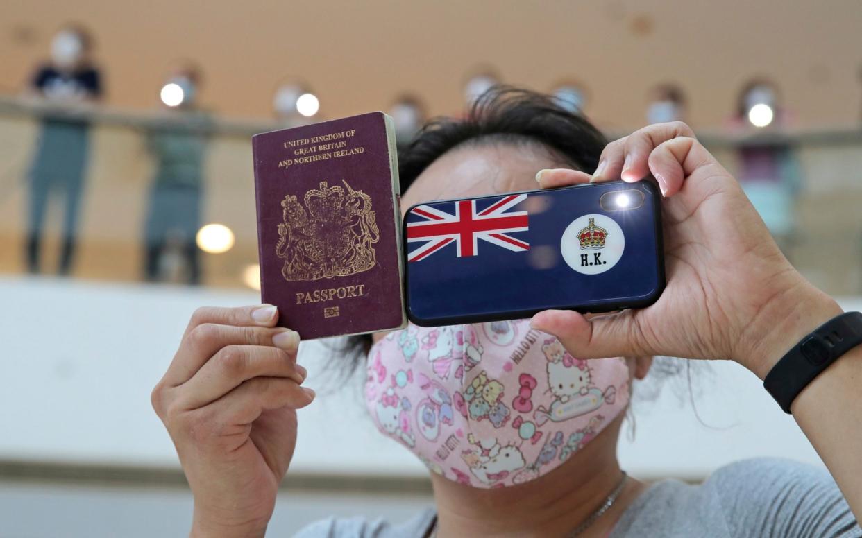 A protester holds a British National (Overseas) passport in a shopping mall during a protest against China's national security legislation for the city, in Hong Kong, Friday, May 29, 2020 - AP Photo/Kin Cheung