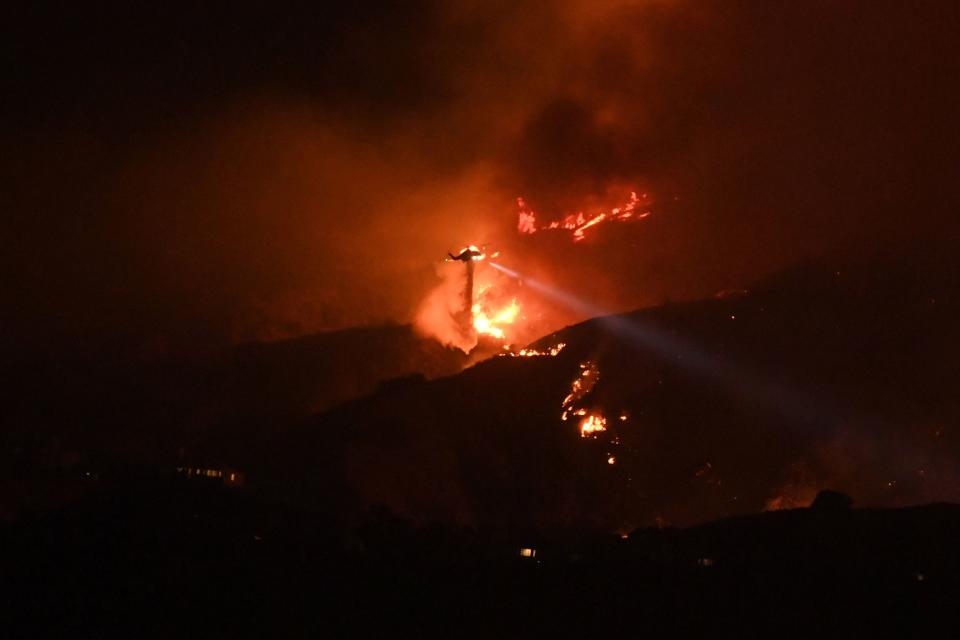 <p>A helicopter drops water on the La Tuna Canyon fire at night in the hills above Burbank, Calif., early Sept. 2, 2017. (Photo: Robyn Beck/AFP/Getty Images) </p>