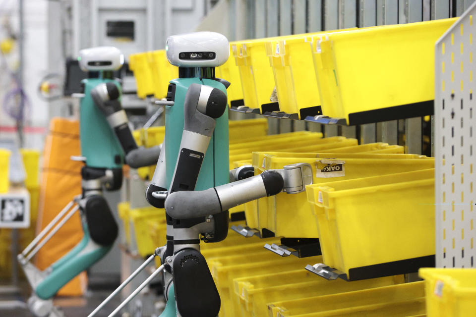 Bipedal robots in testing phase move containers during a mobile-manipulation demonstration at Amazon's 