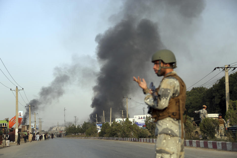 An Afghan police stands guard as smoke billows from the Green Village, home to several international organizations and guesthouses, in Kabul, Afghanistan, Tuesday, Sept. 3, 2019. Angry residents climbed into the international compound that had been targeted and set part of it on fire. (AP Photo/Rahmat Gul)