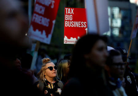 FLE PHOTO: A woman holds a sign supporting the taxation of big businesses during a protest in front of the Amazon Spheres to demand that the city of Seattle tax the largest corporations to help fund affordable housing, according to organizers, in Seattle, Washington, U.S., April 10, 2018. REUTERS/Lindsey Wasson/File Photo