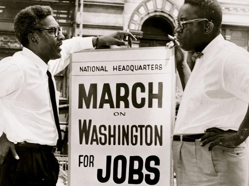 March on Washington Deputy Director Bayard Rustin (1987 - 1987) (left) and Administrative Committee Chairman Cleveland Robinson (1914 - 1995) talk on either side of a sign (advertising the March), at 170 W 130 St, Washington DC, 1963.
