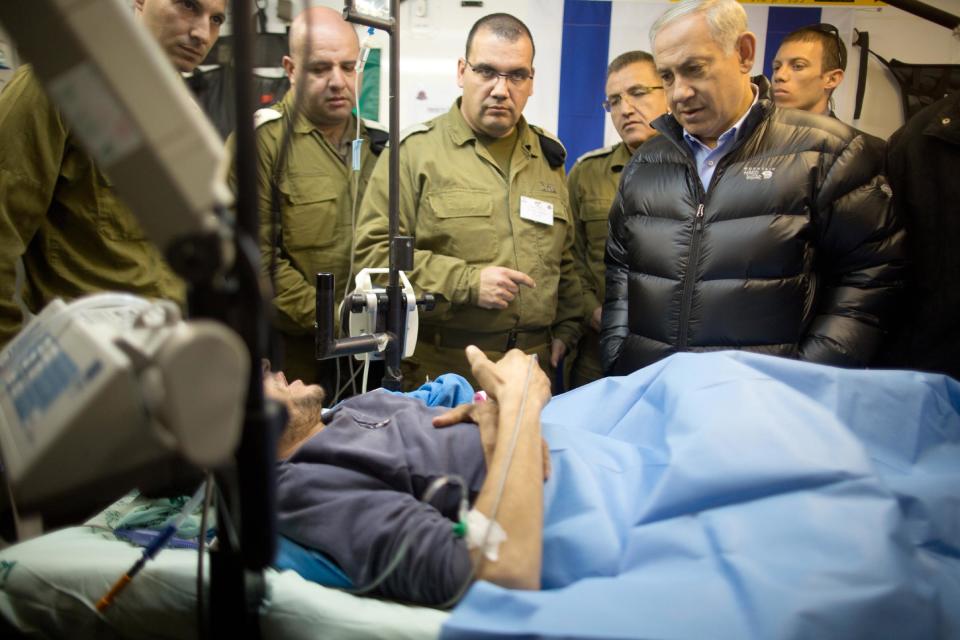 Israeli Prime Minister Benjamin Netanyahu speaks with a Syrian man, who was wounded in the ongoing violence in Syria, as he visits a military hospital located in the Golan Heights near the border with Syria on Tuesday, Feb. 18, 2014. Since the Syrian conflict erupted almost three years ago hundreds of Syrians have received treatment in Israeli hospitals. (AP Photo/Menahem Kahana, Pool)