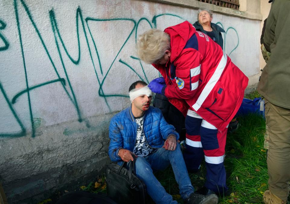 People receive medical treatment on the scene of Russian shelling in Kyiv (AP)