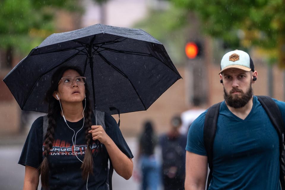 Chermiqua Tsosie, left, a senior at Arizona State University majoring in medical studies, walks in the rain at ASU's downtown Phoenix campus on March 15, 2023.