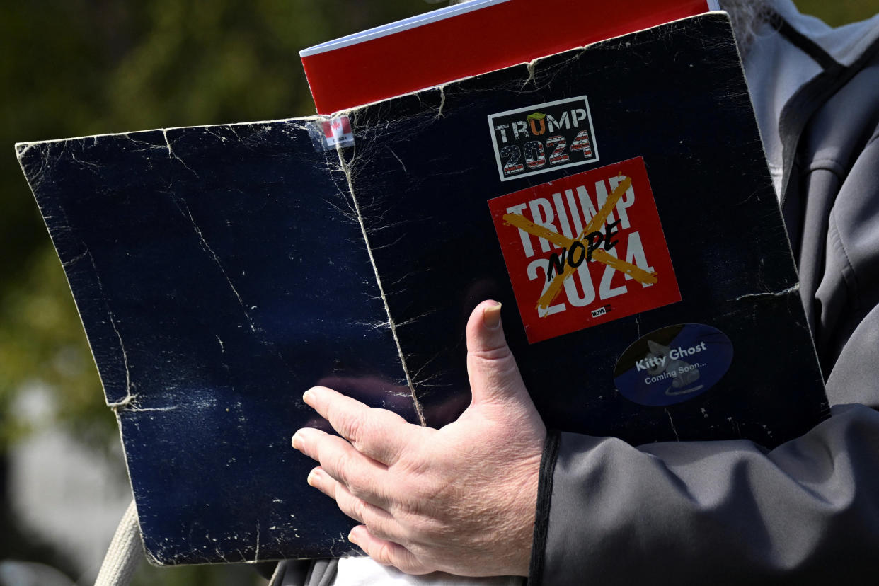 A rally attendee holds a folder with negative stickers about former President Donald Trump 