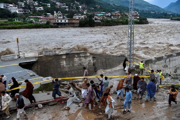 People gather in front of a road damaged by flood waters following heavy monsoon rains in Madian area in Pakistan's northern Swat Valley on Aug. 27, 2022. (Photo: ABDUL MAJEED/AFP/Getty Images)