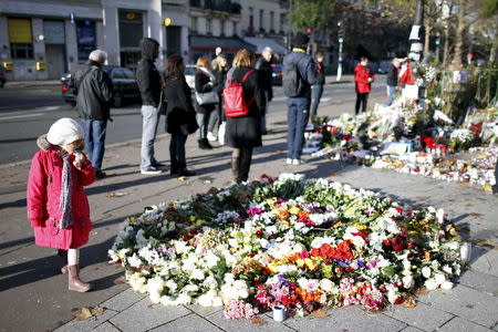 A girl looks at flowers, candles and messages left in memory of victims near the Bataclan concert hall, one of the sites of last Friday's deadly attacks, in Paris, France, November 21, 2015. REUTERS/Charles Platiau
