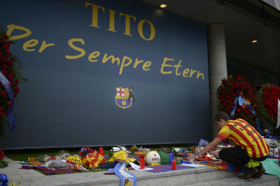 A man places flowers for pay his respect to late former FC Barcelona's coach Tito Vilanova at Camp Nou Stadium in Barcelona, Spain, Saturday, April 26, 2014. FC Barcelona announced on their web page Friday April 25, 2014 that Vilanova has died Friday following a long battle with throat cancer. He was 45. The banner reads in Catalan: "Tito Forever eternal". (AP Photo/Manu Fernandez)