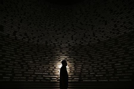 A worker looks at names of the 2004 tsunami victims on a wall at the Aceh Tsunami Museum during preparations for a ceremony in Banda Aceh December 25, 2014. REUTERS/Beawiharta