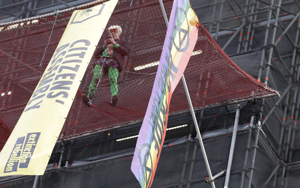 A climate protester demonstrates with banners on the scaffolding covering the Elizabeth Tower that houses the Big Ben clock in London, Friday, Oct. 18, 2019. (AP Photo/Kirsty Wigglesworth)