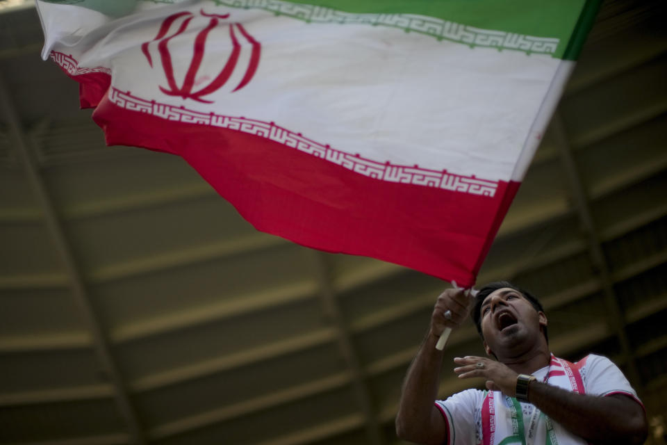 A soccer fan holds a flag from Iran prior to the World Cup group B soccer match between Wales and Iran, at the Ahmad Bin Ali Stadium in Al Rayyan , Qatar, Friday, Nov. 25, 2022. (AP Photo/Francisco Seco)