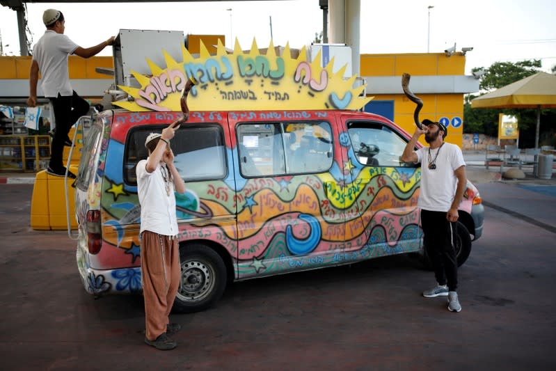 FILE PHOTO: Jewish men blow the Shofar, a ceremonial ram's horn, next to a van in a petrol station in the Israeli settlement of Ofra in the occupied West Bank