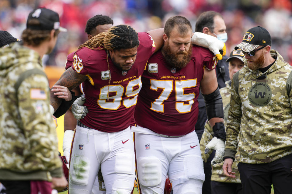 FILE - Washington Football Team defensive end Chase Young (99) is helped off the field by guard Brandon Scherff (75) after an injury during the first half of an NFL football game against the Tampa Bay Buccaneers, on Nov. 14, 2021, in Landover, Md. Young is starting training camp on the physically unable to perform list as he works back from surgery to repair a torn ACL in his right knee. (AP Photo/Nick Wass, File)