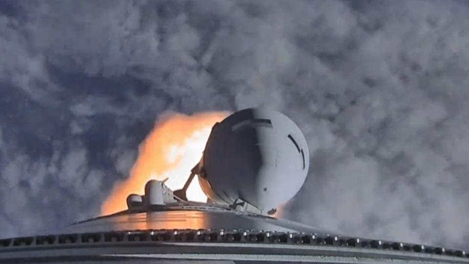 a great white rocket rises out through the cloudy sky above a huge plume of fire and smoke