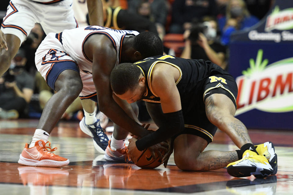 Michigan's DeVante' Jones (12) and Illinois' Da'Monte Williams vie for a loose ball during the second half of an NCAA college basketball game Friday, Jan. 14, 2022, in Champaign, Ill. (AP Photo/Michael Allio)