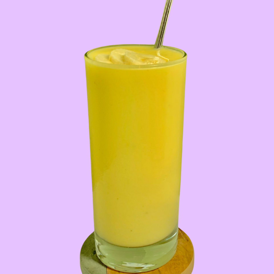 tall glass of a yellow drink with a metal straw