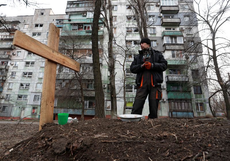 A local resident stands next to the grave of his friend killed during Ukraine-Russia conflict in Mariupol