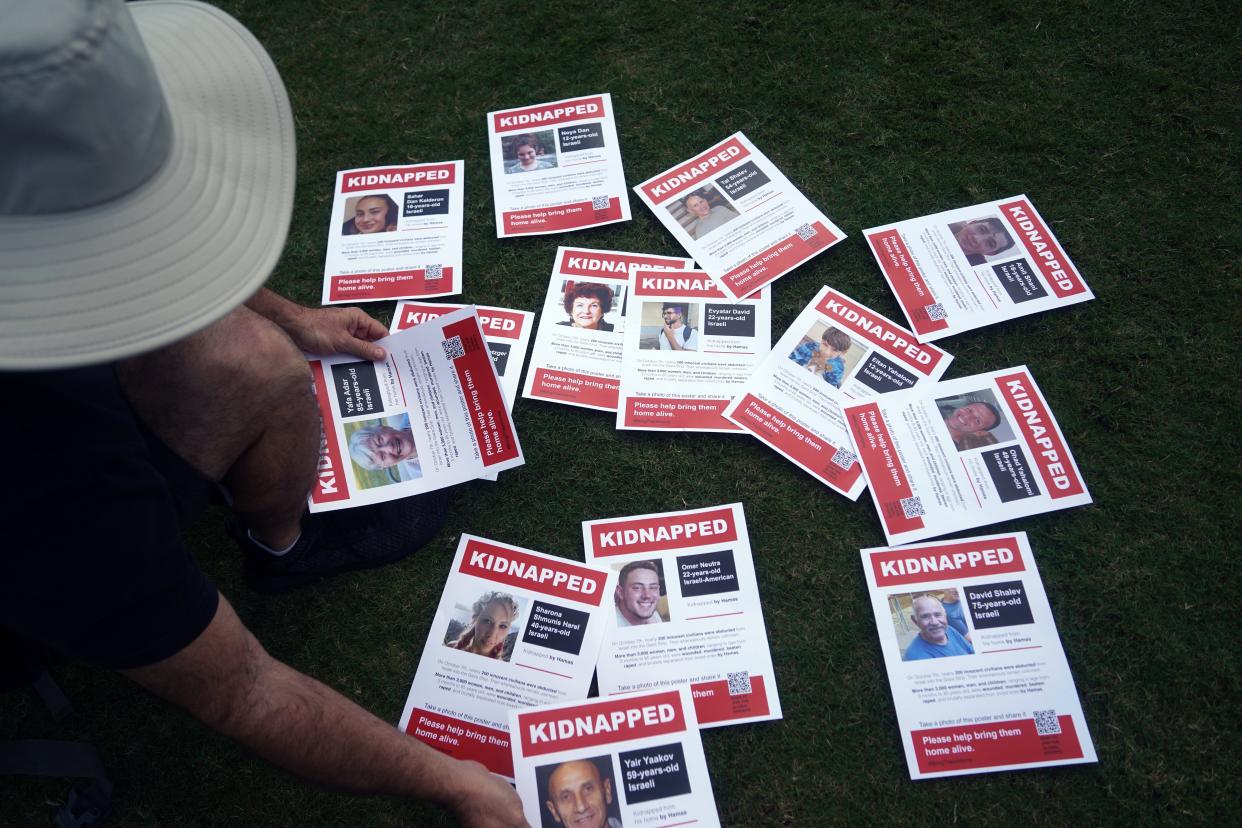Shay Zaidenberg shows flyers of kidnapped Israelis on Sunday afternoon on the Great Lawn in West Palm Beach.