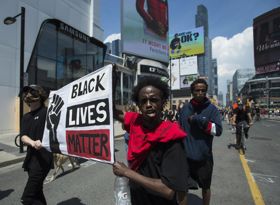 People hold up a Black Lives Matter sign as thousands of people protest at an anti-racism demonstration, in Toronto on Friday, June 5, 2020. George Floyd, a black man, died after he was restrained by Minneapolis police officers on May 25. His death has ignited protests in the U.S. and worldwide over racial injustice and police brutality. (Nathan Denette/The Canadian Press via AP)