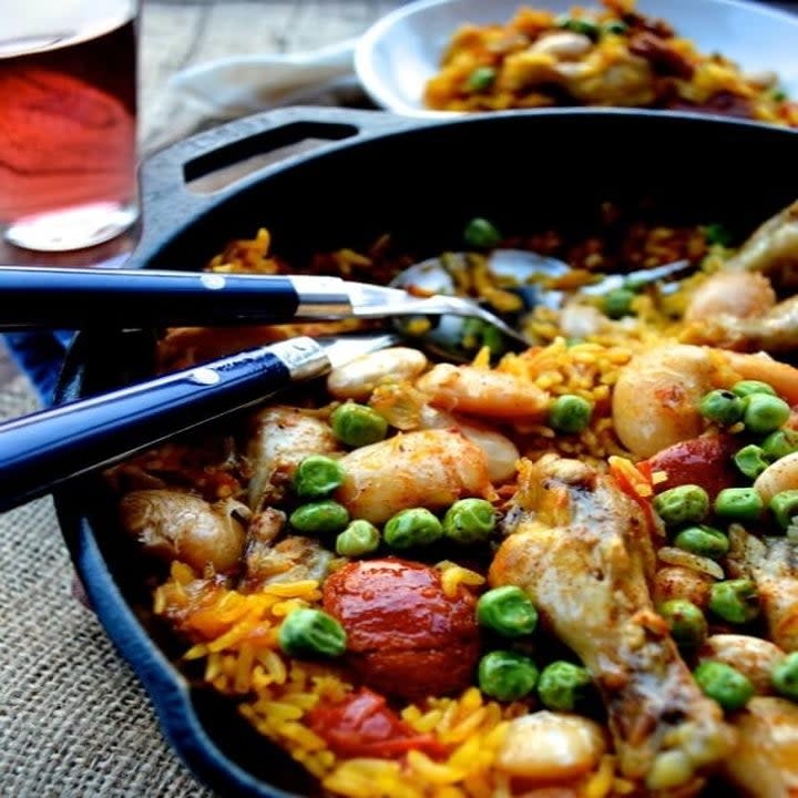 A skillet filled with rice, peas, chorizo, and chicken paella