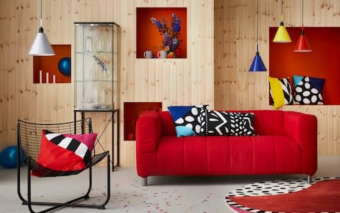 Retro Ikea furnishings including a red sofa, black metal chair and light fittings in blue, white, red and yellow 