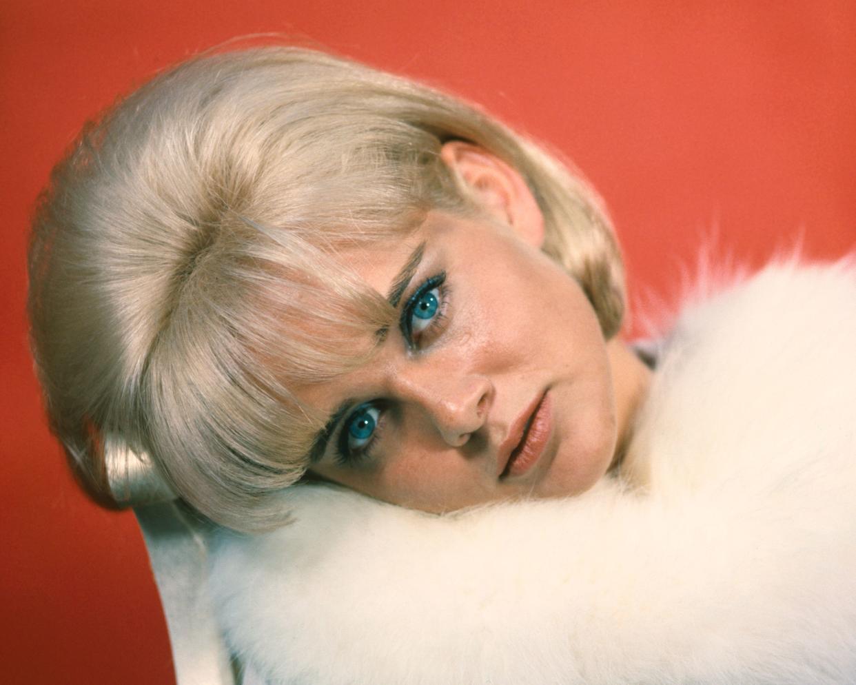 Sue Lyon tilts her head while wearing a white fur shawl