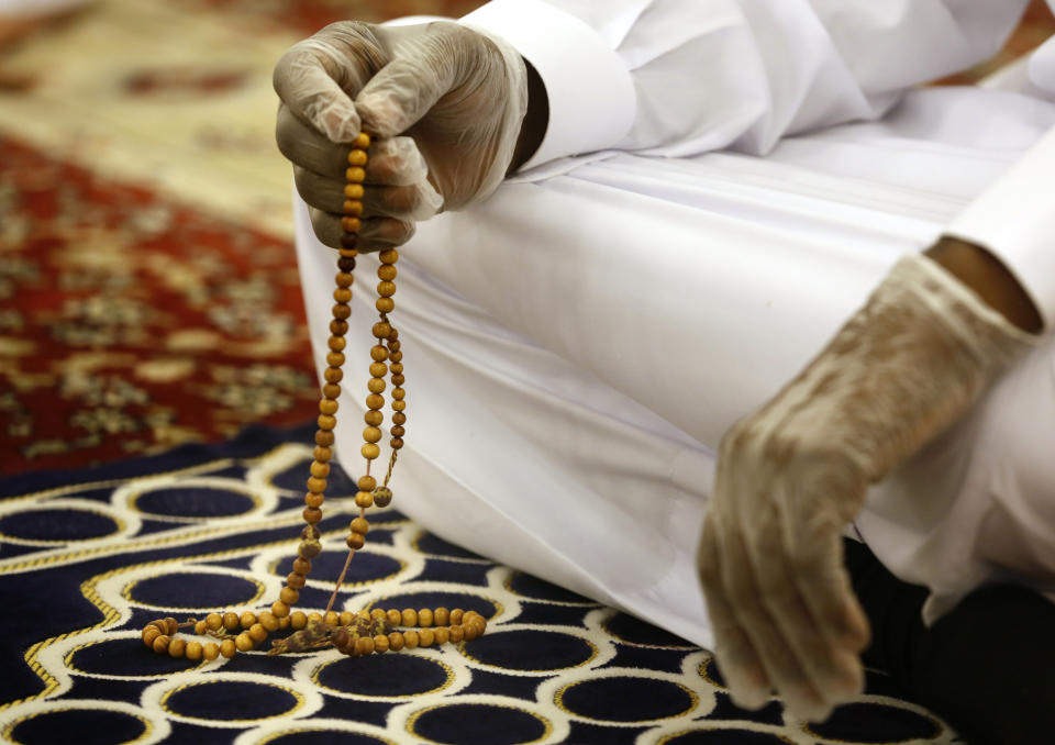 A worshipper wearing surgical gloves to prevent the spread of COVID-19 prays at al-Mirabi Mosque in Jiddah, Saudi Arabia, Sunday, May 31, 2020. The Ministry of Islamic Affairs said mosques will open to the public for prayers from May 31 until June 20, except in Mecca, with precautionary measures and instructions. (AP Photo/Amr Nabil)