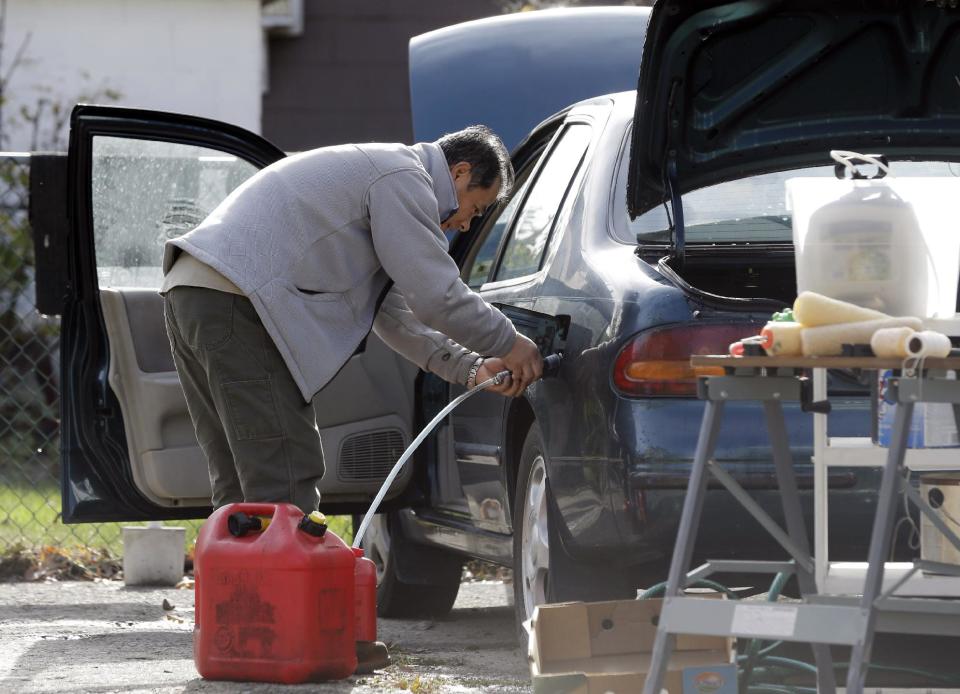 Toshi Ogawa siphons gasoline from his car to use in a generator at his house which is without power in the wake of superstorm Sandy on Thursday, Nov. 1, 2012, in Little Ferry, N.J. New Jersey residents across the state were urged to conserve water. At least 1.7 million customers remained without electricity. (AP Photo/Mike Groll)